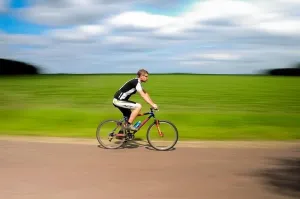 Uśmiechnięta kobieta w salonie fryzjerskim prezentuje świeże, naturalne pasemka blond na średniej długości brązowych włosach.